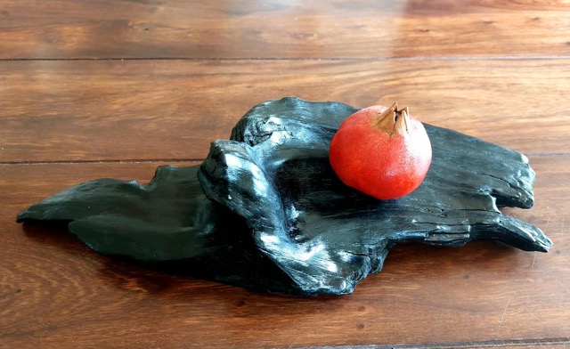 Granatapfel aus Keramik auf einem Stück Mooreiche